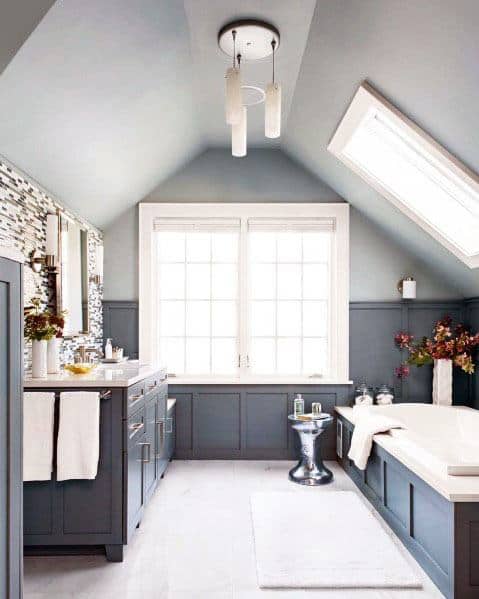 Bright bathroom with navy cabinetry, skylight, freestanding tub, and mosaic accent wall.