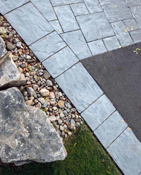 Stylish driveway edging with smooth river rocks, complemented by stone tiles and large rocks, creating a clean, modern look