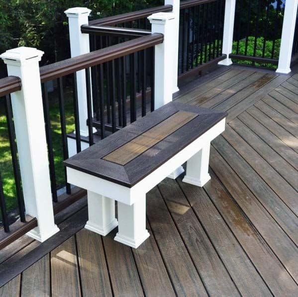 Deck with brown bench seating, white posts, and black railings, all overlooking a lush green lawn