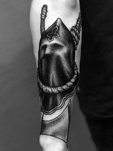Detailed black and grey executioner tattoo featuring a hooded figure with a cross emblem and a large axe, shaded for depth and realism.