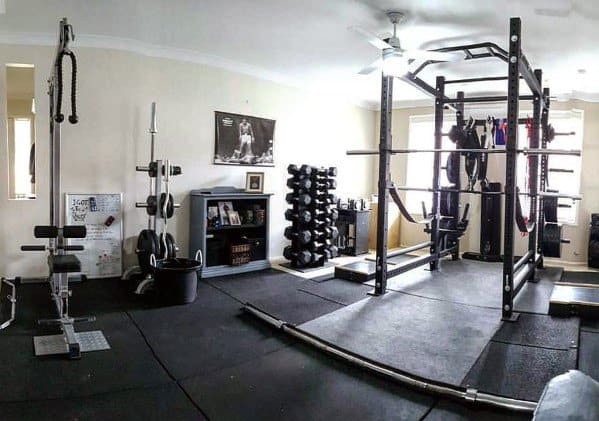 Garage gym with power rack, dumbbell rack, weight plates, and cable machine setup.
