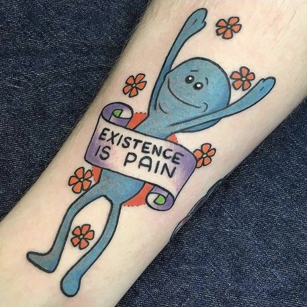 A colorful tattoo of a blue cartoon figure with a happy face holding a banner that reads 'EXISTENCE IS PAIN,' surrounded by small flowers.