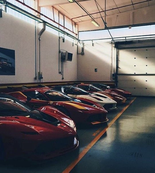 Classic garage featuring a checkered floor, vintage Ferraris, and a well-organized luxury car collection.