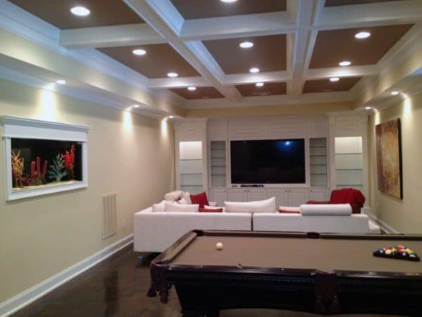 Basement with coffered ceiling, pool table, sectional sofa, and built-in entertainment center.