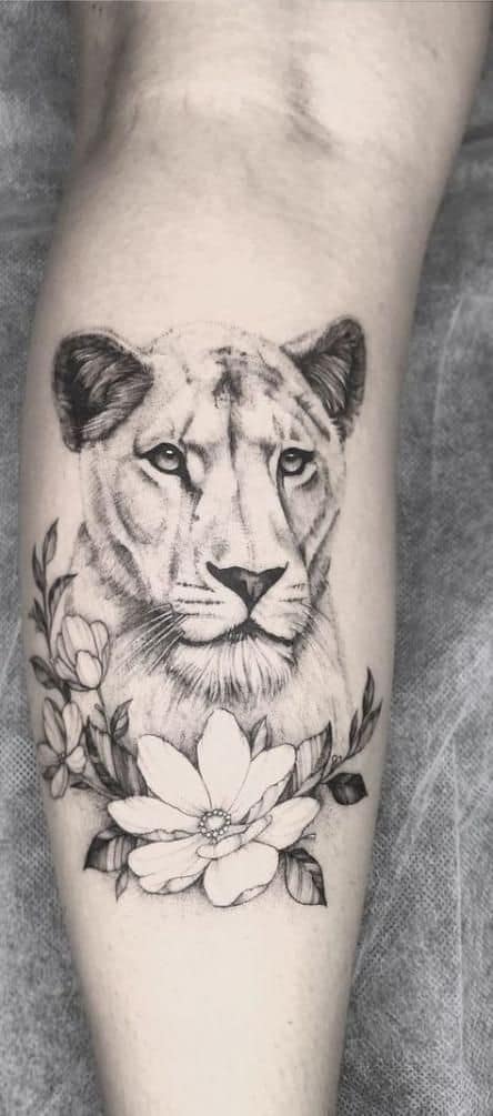 Black and grey lioness tattoo on the forearm, featuring realistic shading, delicate floral details, and fine linework for a soft yet powerful look.