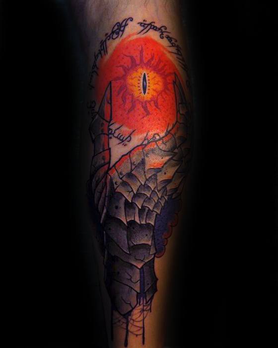 Tattoo of a red Eye of Sauron with black text and abstract designs on a person's arm