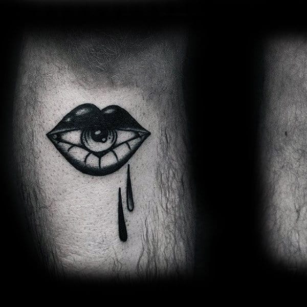 Tattoo of a crying eye within lips on skin, with two black teardrops