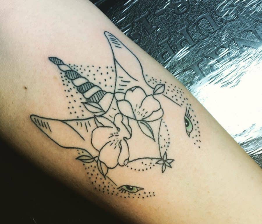 Minimalist unicorn tattoo with floral elements and dotwork detailing, featuring striking green eyes for a mystical and artistic design.