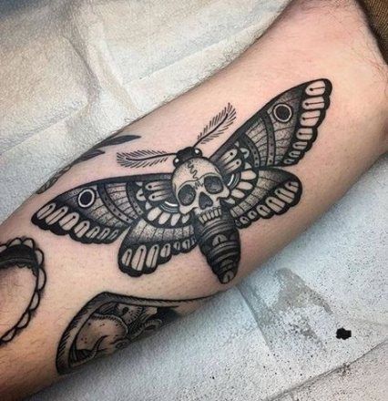 Bold black and grey death moth tattoo with a skull centerpiece, symbolizing mystery, transformation, and the cycle of life and death.