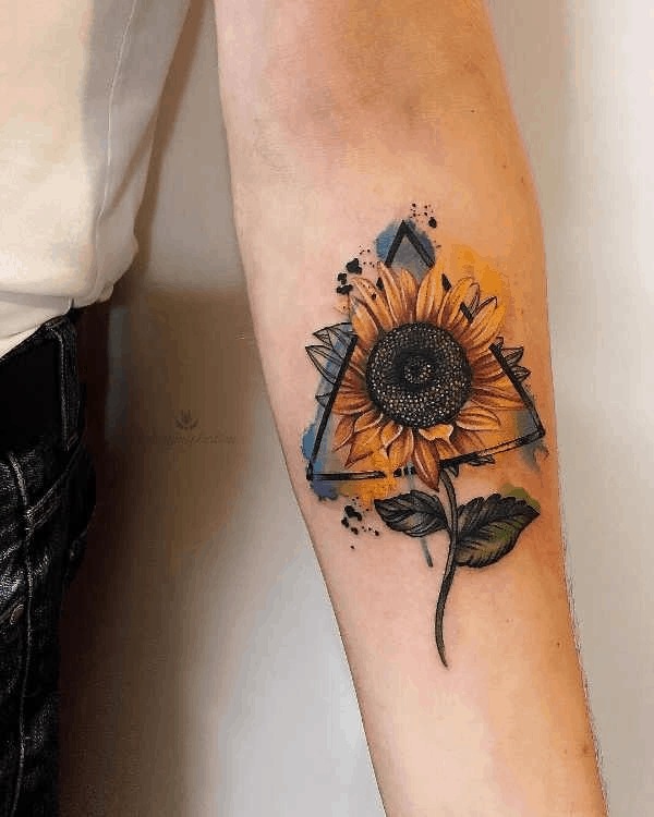 Colorful sunflower tattoo on forearm with a geometric triangle frame, watercolor splashes, and fine line details for a bold artistic design.