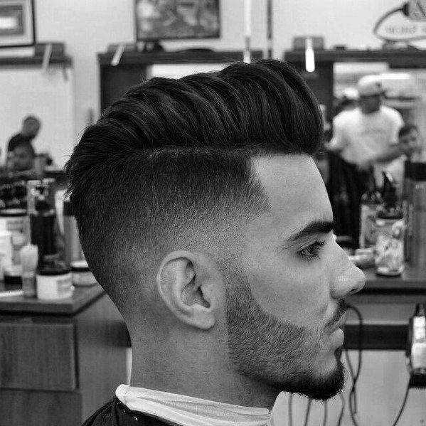 Voluminous, textured quiff with a high fade on the sides and a sharp lineup at the hairline and beard