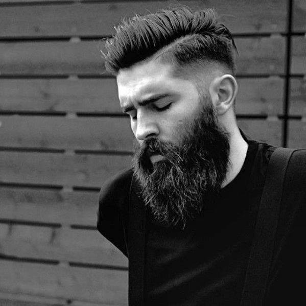 Textured, combed-back top with a high fade on the sides and back, complemented by a full, thick beard