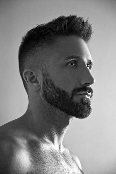 Short, spiky top with a high fade on the sides and back, complemented by a well-groomed, full beard