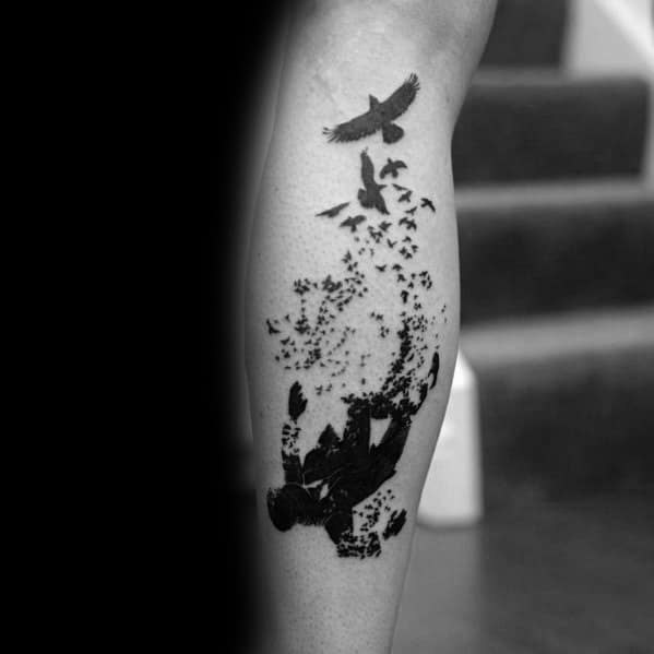 Artistic tattoo of a falling figure dissolving into birds mid-air, symbolizing transformation or freedom, inked on the calf.