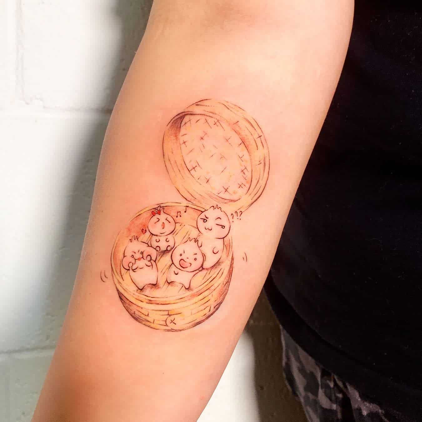 Tattoo of cute dumplings with faces inside a bamboo steamer basket