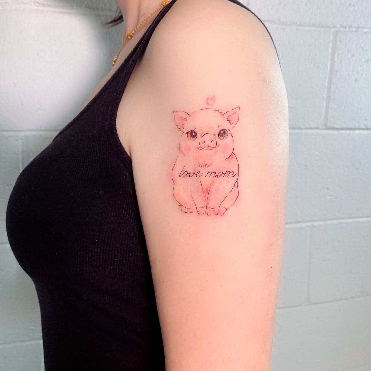 Tattoo of a cute pink piglet with "love mom" written on its body