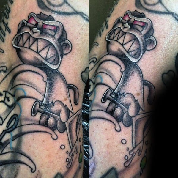 Tattoo of the Evil Monkey from Family Guy in black and gray, showing an aggressive stance with sharp teeth, red eyes, and a menacing expression.