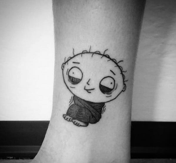 Tattoo of Stewie Griffin from Family Guy in a minimalist black and gray style, sitting cross-legged with a soft, innocent expression.