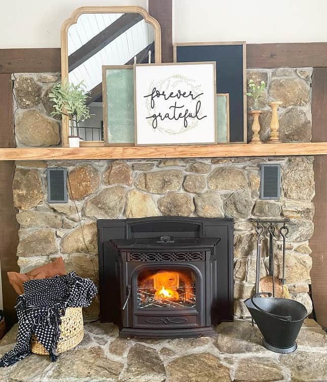 stone fireplace with wood mantel holding frames