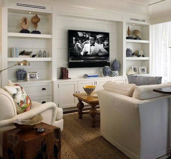 Cozy family room with built-in bookcases, TV centerpiece, white furniture, and nautical-themed decor accents