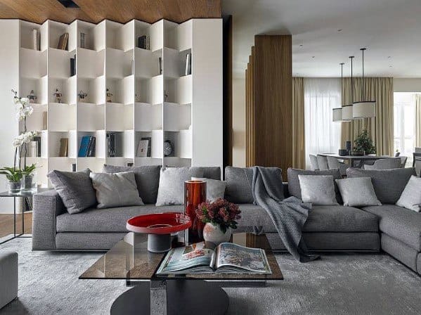 Modern living room with gray sofas, a glass table, bookshelves, and decorative items