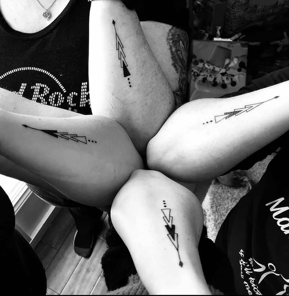 Matching sister sibling tattoos featuring geometric arrow designs with dots, and the shades represent their birth order