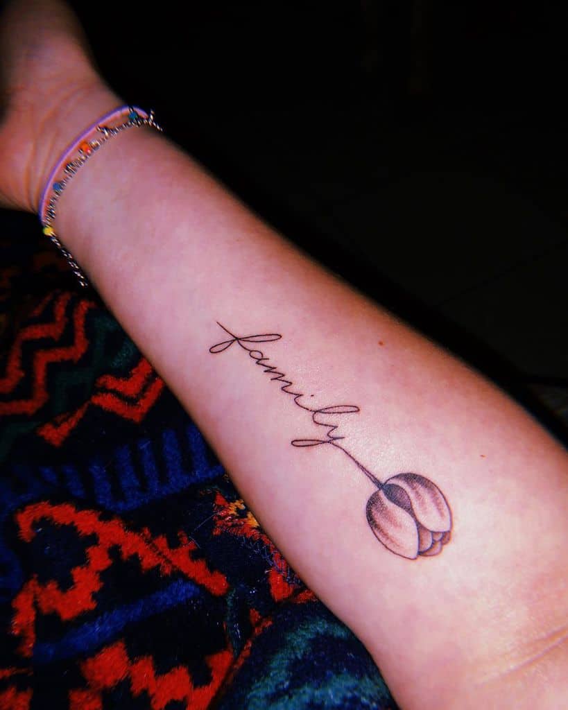 A forearm tattoo featuring a delicate tulip with its stem transitioning into the cursive word "family," symbolizing love and connection.