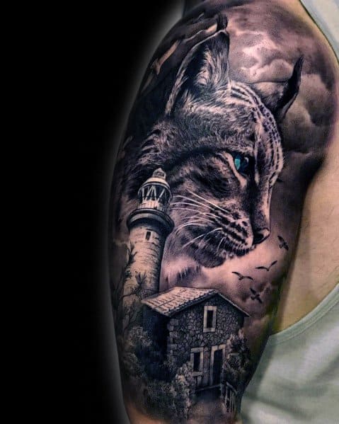 Realistic black and gray cat tattoo on the upper arm, featuring a lighthouse and stormy sky for a dramatic and detailed design.