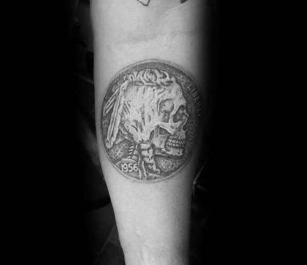 Detailed tattoo of a 1956 hobo nickel featuring a skull design, blending realism and dark artistry for a unique coin-inspired piece.