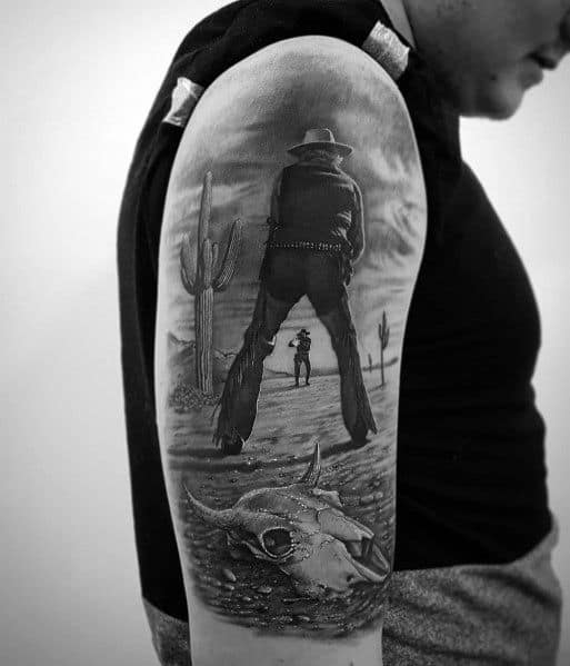 Black and gray tattoo of a dramatic Western standoff, featuring two cowboys in a desert landscape with cacti and a skull in the foreground.