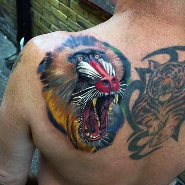 Realistic baboon shoulder tattoo with vivid colors, intense shading, and a fierce open-mouthed expression, creating a bold and dynamic design.