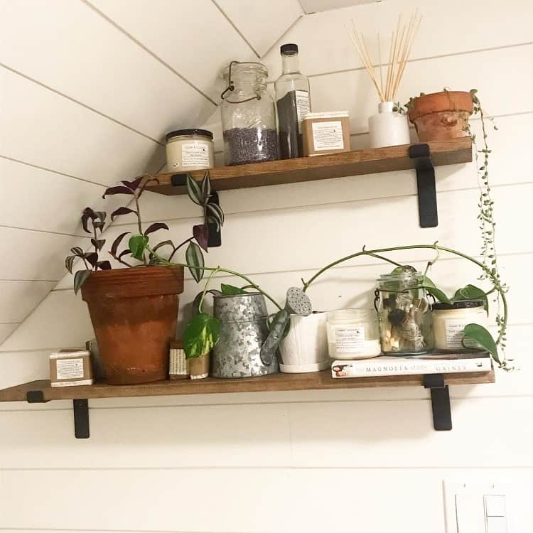 Farmhouse bathroom shelves with potted plants, candles, jars, and rustic decor accents.