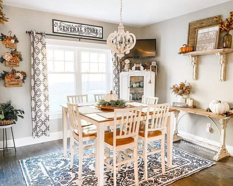 Cozy farmhouse dining room with patterned curtains, rustic decor, and a vintage chandelier.