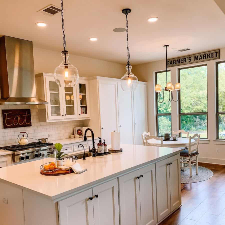 Bright farmhouse kitchen with large windows, pendant lighting, and a cozy dining nook.