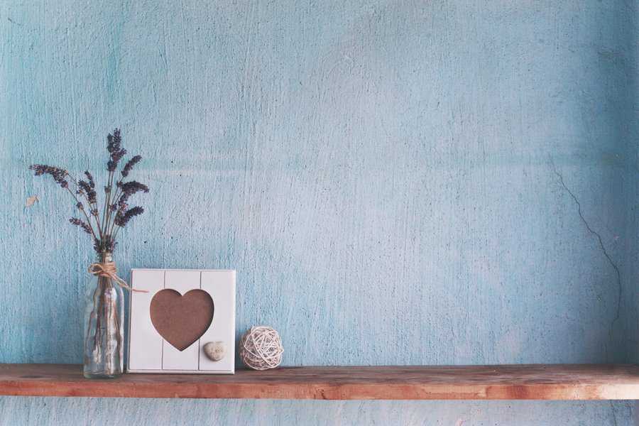 Lavender in glass vase and blank photo frame on a vintage shelf over pastel wall