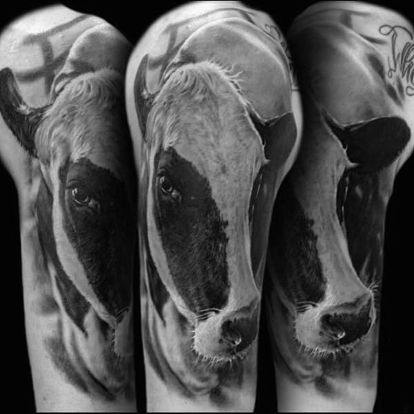 Hyper-realistic black and gray shoulder tattoo of a cow’s face, with detailed shading capturing lifelike fur and expression.