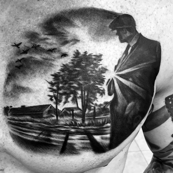 Black and gray chest tattoo of a man in a suit looking over farmland with trees, barns, and flying birds, radiating light from his chest.