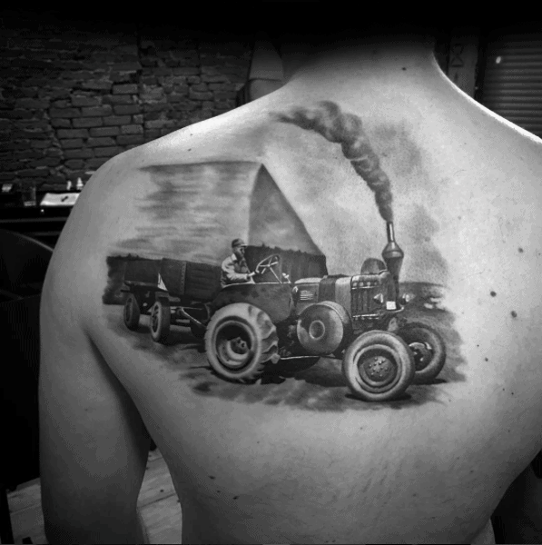 Realistic black and gray back tattoo of a vintage steam tractor pulling a trailer with a farmer driving in front of a barn.