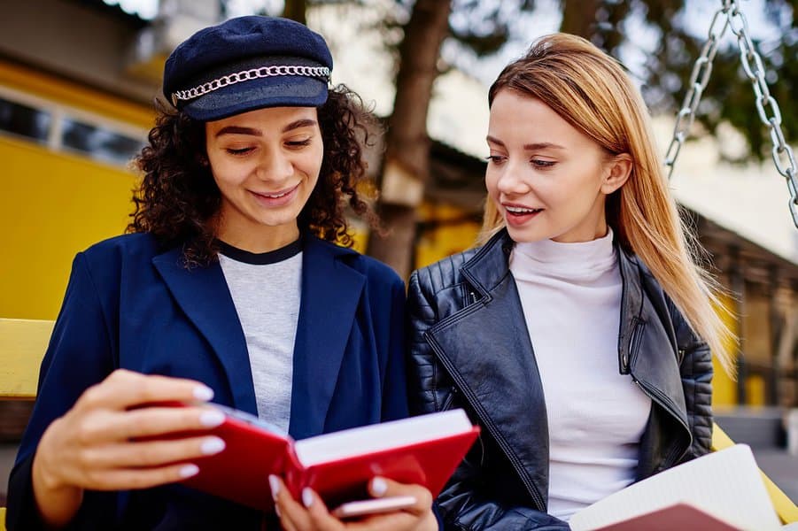 female friends reading notes in diaries with interest