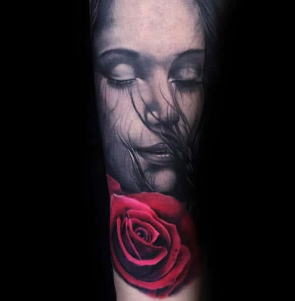 Tattoo of a serene woman's face with flowing hair and a vivid red rose