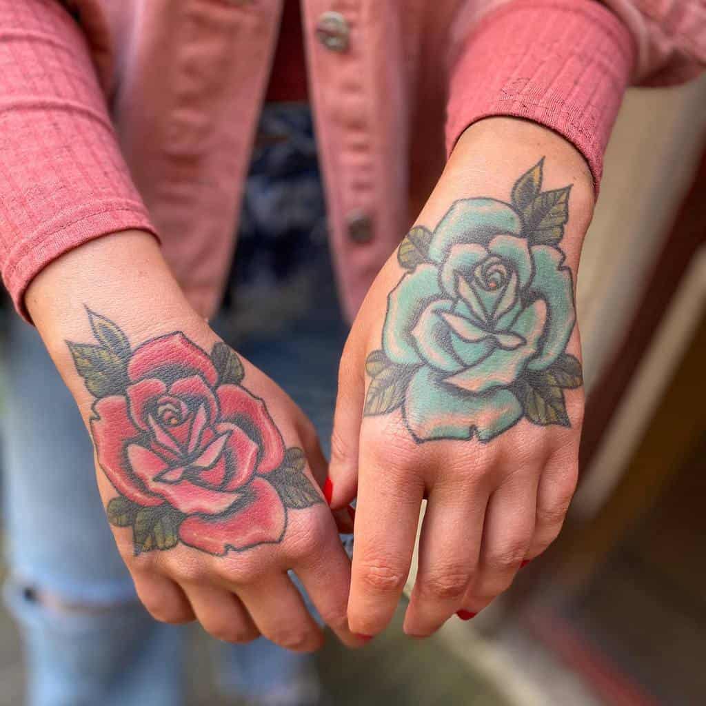 A pair of hand tattoos featuring a red rose on the left hand and a blue rose on the right, both with green leaves and bold outlines