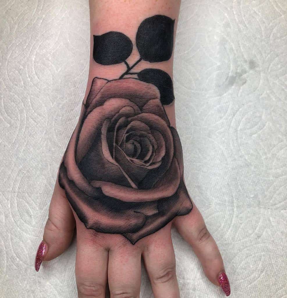 A hand adorned with a detailed black rose tattoo
