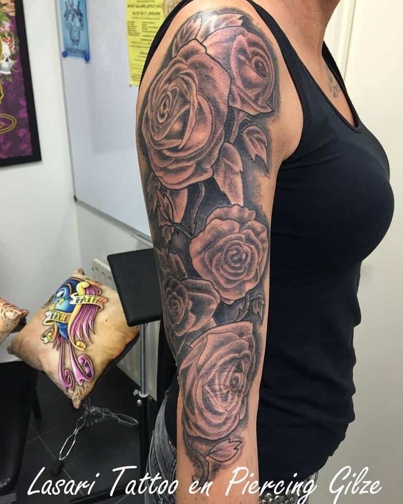 An arm adorned with an intricate sleeve of rose tattoos