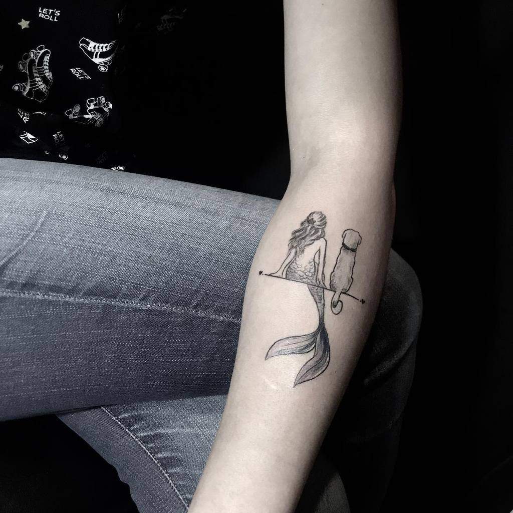 Minimalist black and grey tattoo of a mermaid and a dog sitting on a thin line, gazing into the distance, symbolizing companionship