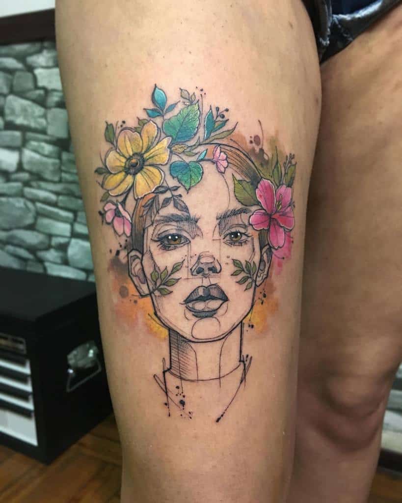 Tattoo of a woman's face with flowers in her hair, featuring vibrant colors and abstract lines