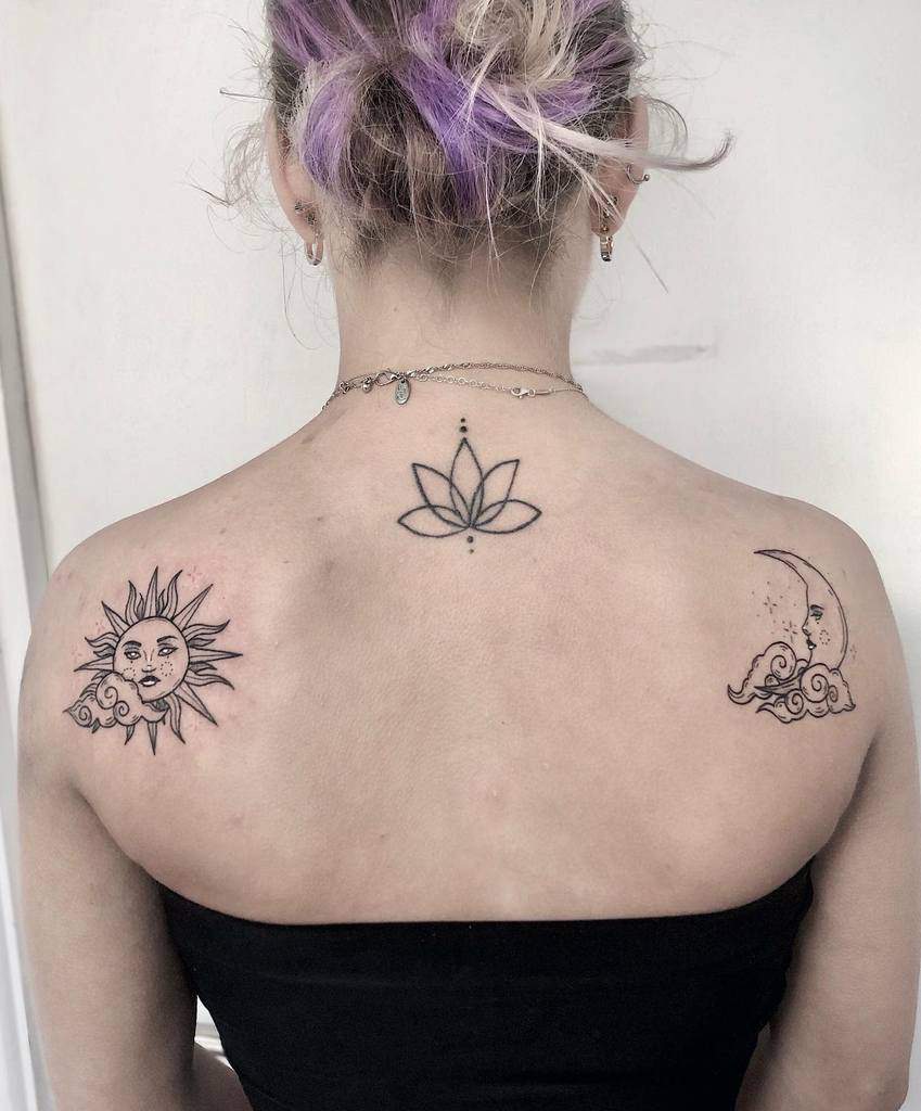 A tattoo featuring a sun with a cloud on the left, a lotus flower in the center, and a crescent moon with a cloud on the right