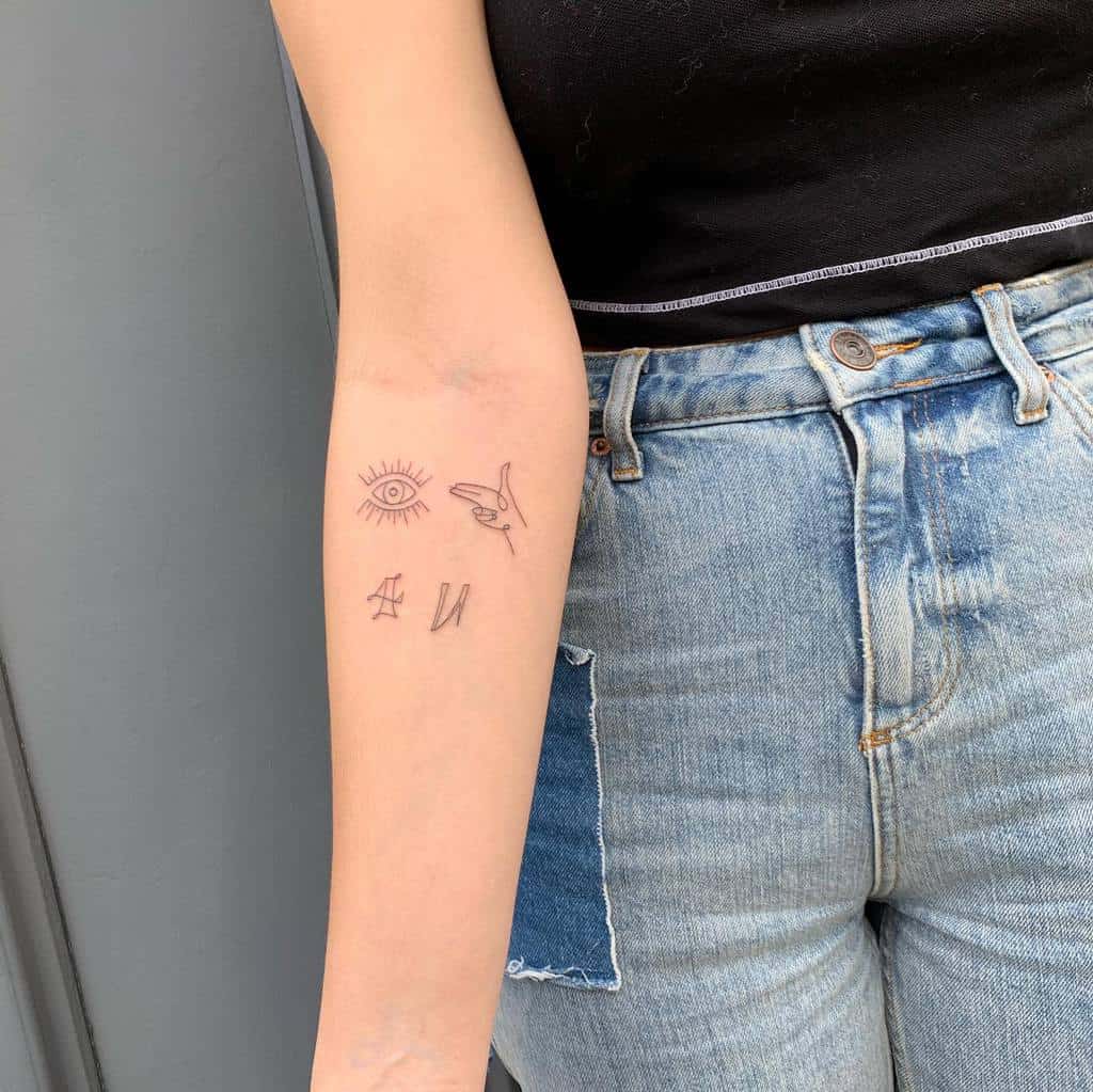 Minimalist fine-line tattoo featuring an eye with rays, a small bird in flight, and abstract symbols