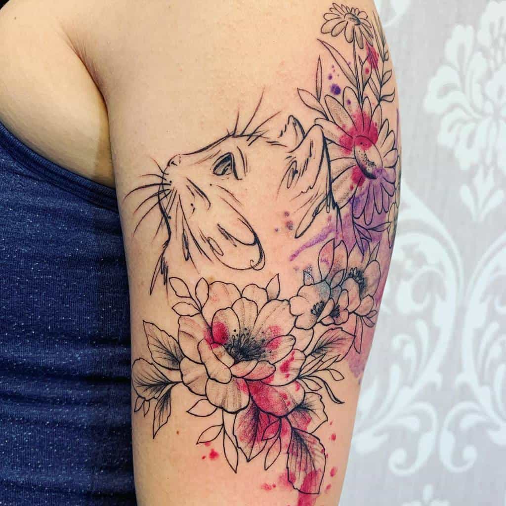 Elegant black ink tattoo of a cat gazing upwards, surrounded by delicate flowers with watercolor-style pink and purple splashes