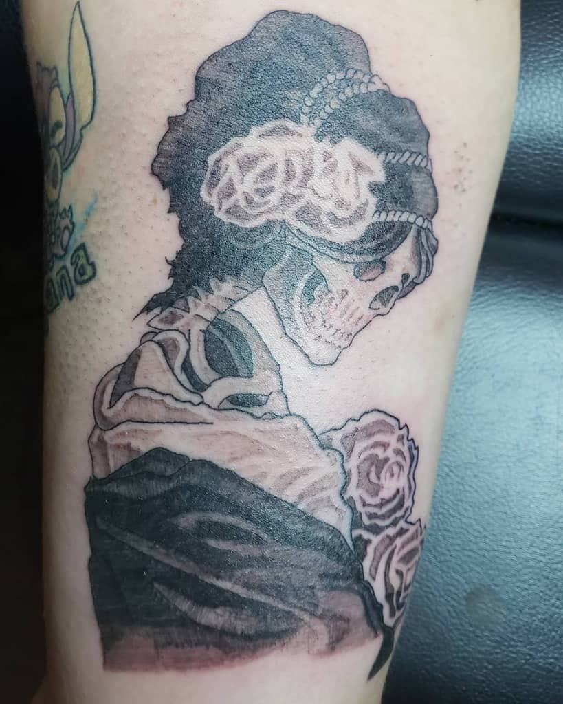 Black and grey tattoo of a skeletal woman in Victorian attire, adorned with roses and pearls, blending gothic and vintage aesthetics.