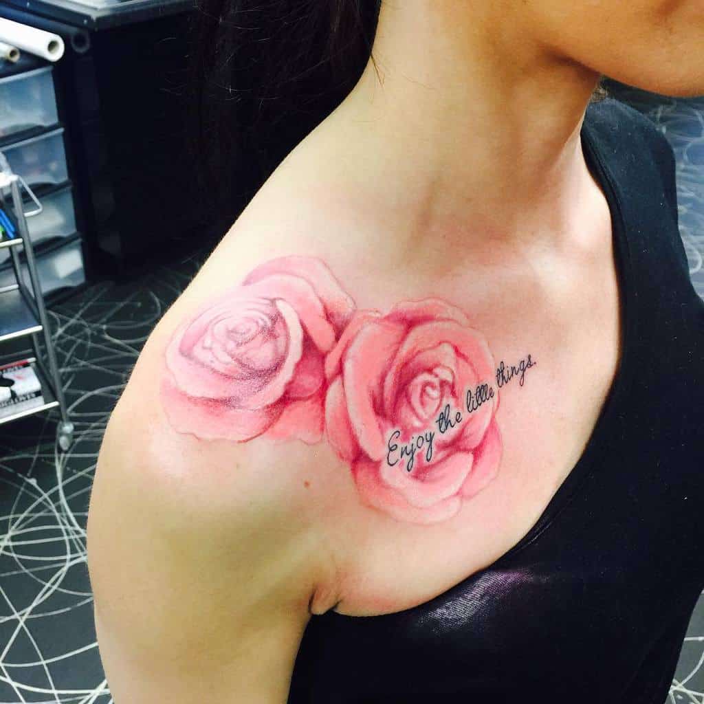 Tattoo of delicate pink roses gracing a woman's shoulder, accompanied by the phrase "Enjoy the little things"